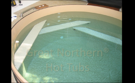 <p>Interior view of a large exercise and hydrotherapy tub, showing bench seats that also serve as steps to enter and exit the 6’ deep tub.</p>