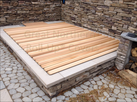 <p>Wooden roll-up cover on a rectangular in-ground stone spa.</p>