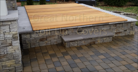 <p>Western red cedar roll-up spa cover on cement spa surrounded by rock trim.</p>