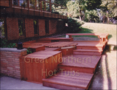<p>Redwood hot tub built into a multi-level deck in a backyard patio-garden setting.</p>