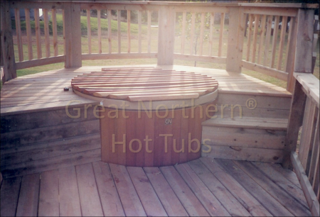 <p>Round cedar wood hot tub with unique wood roll-up cover in a 2 Level Deck with steps.</p>