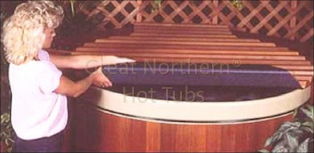 <p>Woman rolling back an insulating wooden roll-up cover on a round cedar hot tub.</p>
