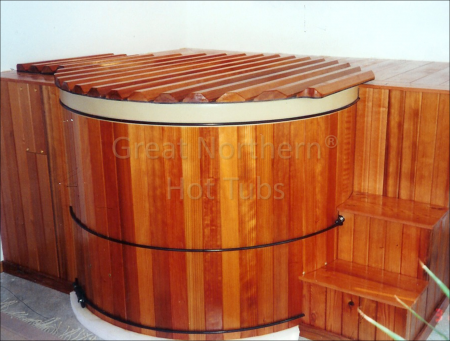<p>Indoor hot tub installation surrounded by a flush deck for seating accessed by steps on either side.</p>