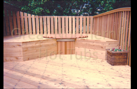 <p>Cedar hot tub on a large wood deck surrounded by a second level that provides flush seating around the tub.</p>