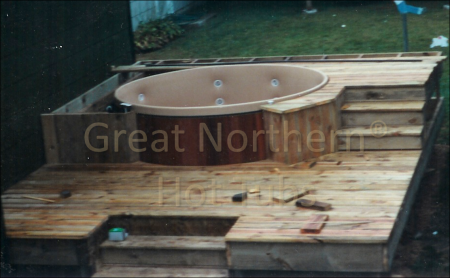 <p>Two-level deck being constructed around a cedar hot tub. Construction almost complete.</p>