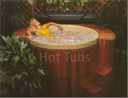 <p>Woman in yellow swimsuit relaxing in a round cedar hot tub surrounded by stepped deck and Roll-Up® Cover conveniently stored nearby.</p>