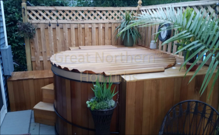 <p>A round cedar hot tub in a backyard corner with surrounding seating and a privacy fence.</p>