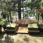 Outdoor cedar hot tub built into a deck, surrounded by a woodsy natural setting for a tranquil escape