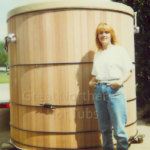Woman standing in front of a large cedar hot tub, showcasing its impressive size and design