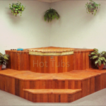 Indoor cedar hot tub surrounded by plants with a custom rollup cover for a serene and stylish atmosphere