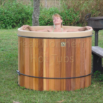 Woman relaxing in an outdoor cedar hot tub, enjoying a peaceful and soothing experience