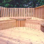 Outdoor cedar hot tub built into a spacious wooden deck for a luxurious and integrated design