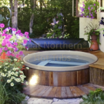 Redwood hot tub in an outdoor garden setting with a custom wooden surround for a natural and elegant look