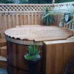 Cedar hot tub with a custom-fit rollup cover in a private outdoor setting surrounded by nature