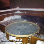 Outdoor cedar hot tub in a snowy setting, offering warmth and relaxation amidst winter surroundings