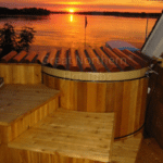 Modern cedar hot tub with a rollup cover in a cozy backyard setting overlooking lake