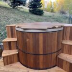 Redwood hot tub with custom outdoor steps built around it for easy access and enhanced design