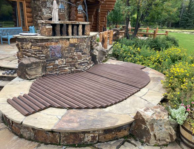 Roll-up cedar cover blends beautifully with stone patio—form meets function in style.