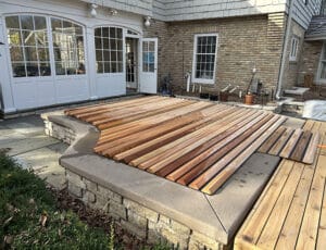 Custom cedar roll-up cover adds warmth and elegance to this stone-wrapped backyard spa setting.